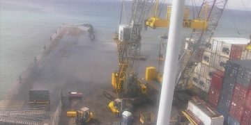 Containers wash off flooded cargo dock