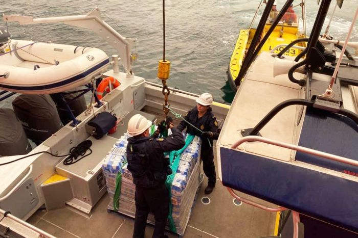 Supplies being taken off the Far Saracen ship off Mallacoota onto a smaller boat.