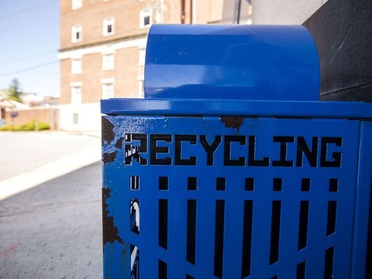 The city of Asheville does own and service the blue recycling bins downtown and in West Asheville. They're usually paired with a black, metal garbage bin.