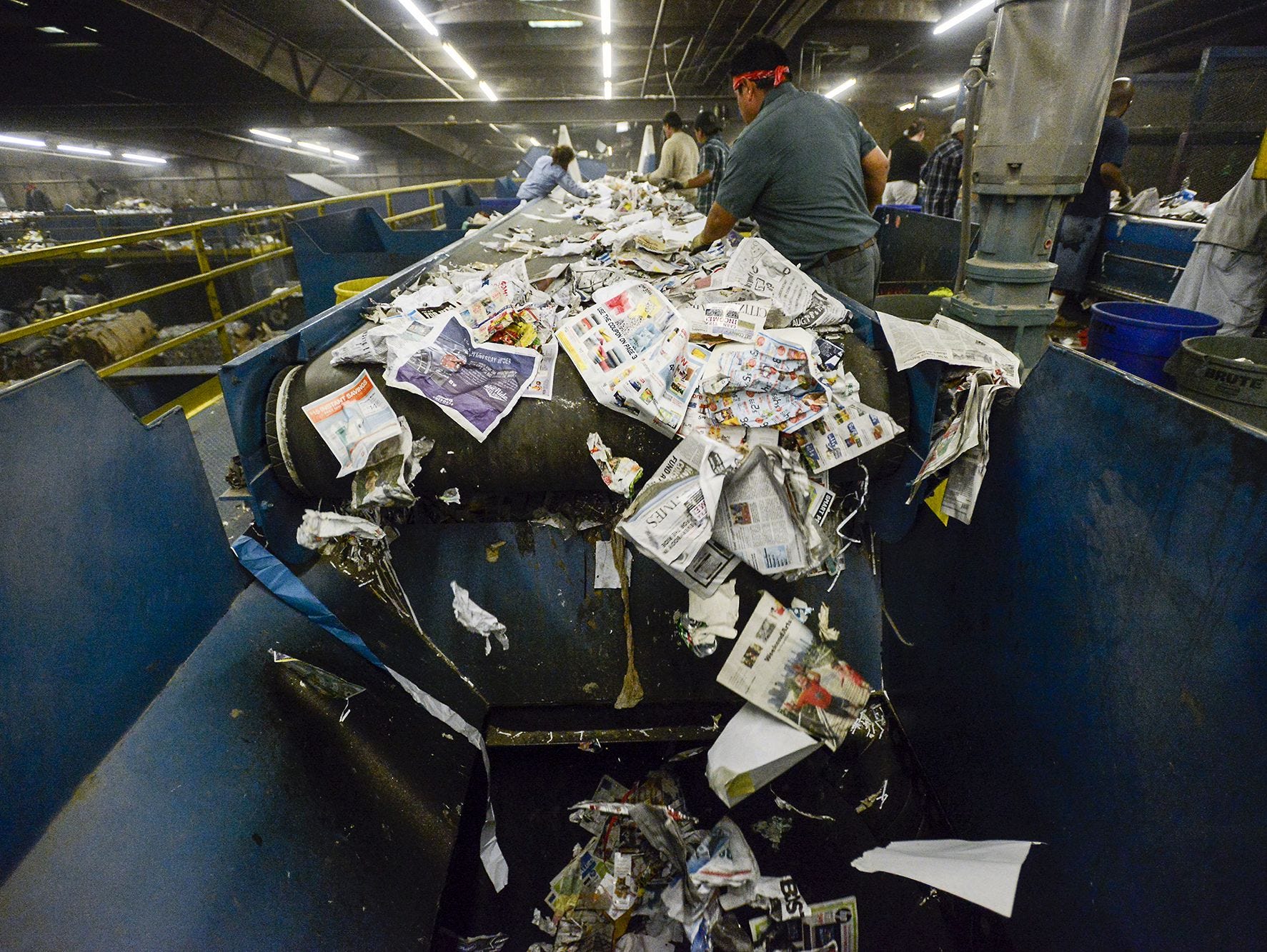 Recycled paper falls down a shoot from a conveyor belt after being sorted by employees at the Curbside Management recycling center in Woodfin, Wednesday, Aug. 20, 2014. Employees have to weed out non-recyclable items, such as plastic bags, and sort through others not meant for the paper section. Curbside Management, or Curbie, handles recycling for the city of Asheville and its 30,000 customers, as well as for Fletcher, Woodfin and Weaverville.