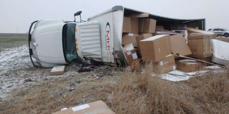 Box truck catches wind, overturns, spills cargo in wheat field