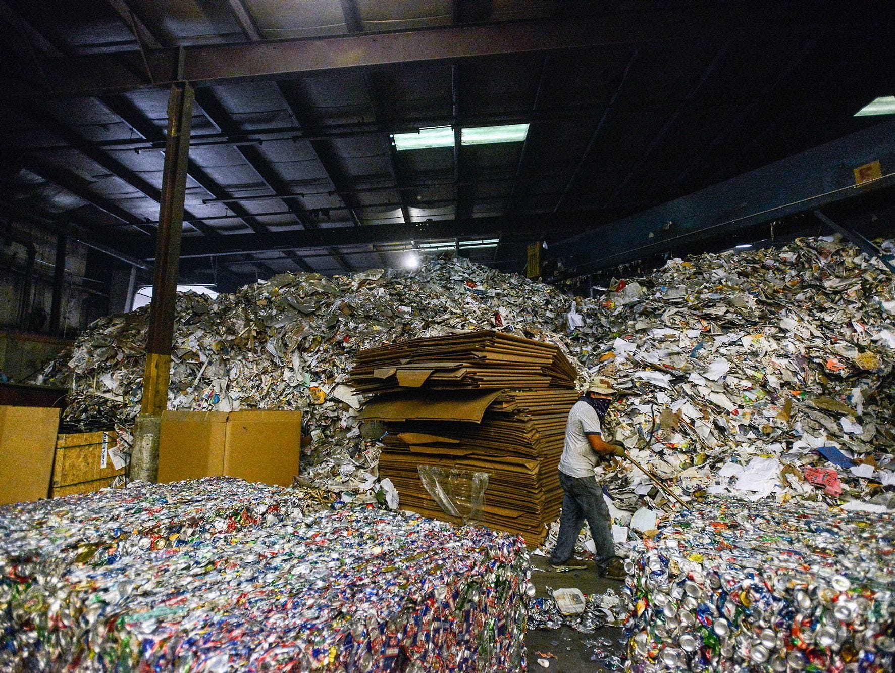 In this file photo, Jose Ramos pushes crushed cans off the floor inside the Curbside Management recycling center in Woodfin. Curbside Management, or Curbie, handles recycling for the city of Asheville and its 30,000 customers, as well as for Fletcher, Woodfin and Weaverville. Curbie does recycle plastics, sending them to a carpet manufacturing company.