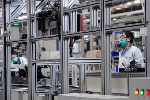 Employees wearing face masks work on a car seat assembly line in Shanghai, China.