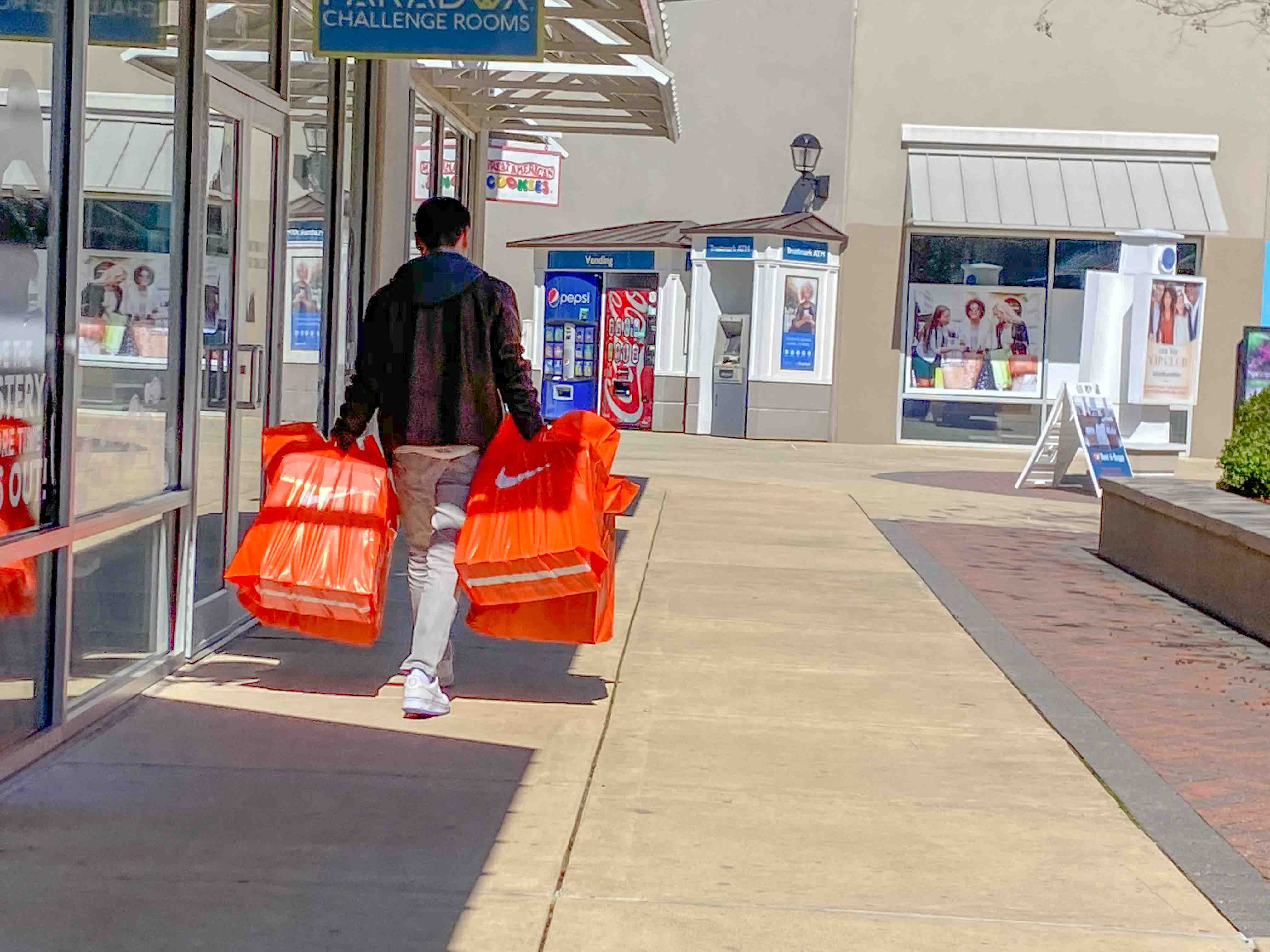 A shopper at Outlets of Mississippi in Pearl, Miss., carries bags from a Nike store Friday, Feb. 21, 2020.